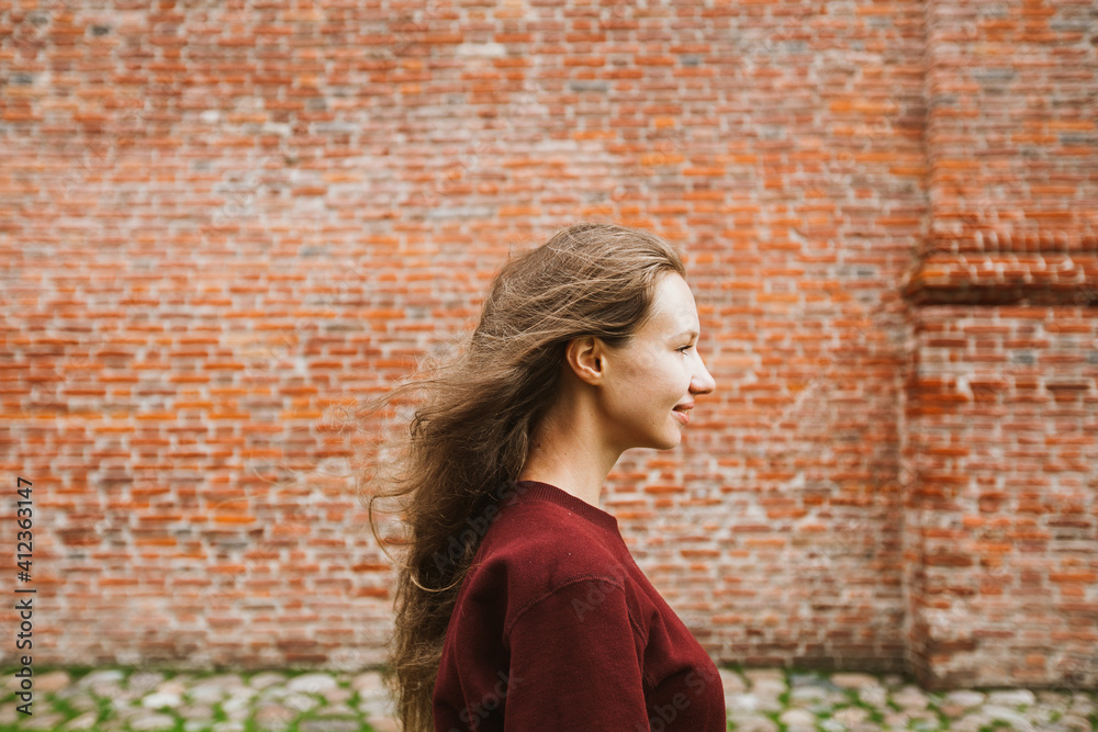 Profile of young woman against brick wall Profile of young woman against brick wall