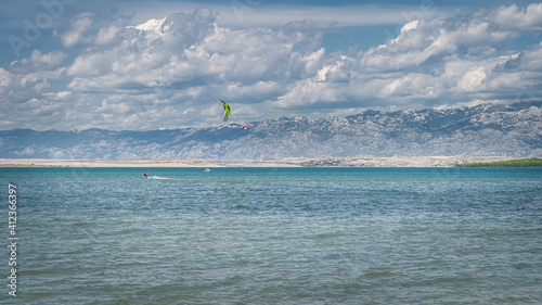View from Zdrijac beach between Nin bay and Adriatic Sea on kite surfers or kitesurfing with mountain range of Dinaric Alps in background, Croatia