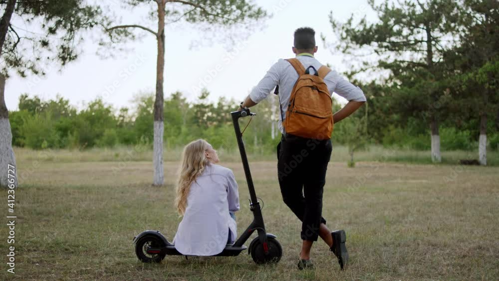 Taking video from the back two office workers after the work they came to the park and lady take a sit down on the electric scooter. 4k Taking video from the back two office workers after the work they came to the park and lady take a sit down on the electric scooter. 4k