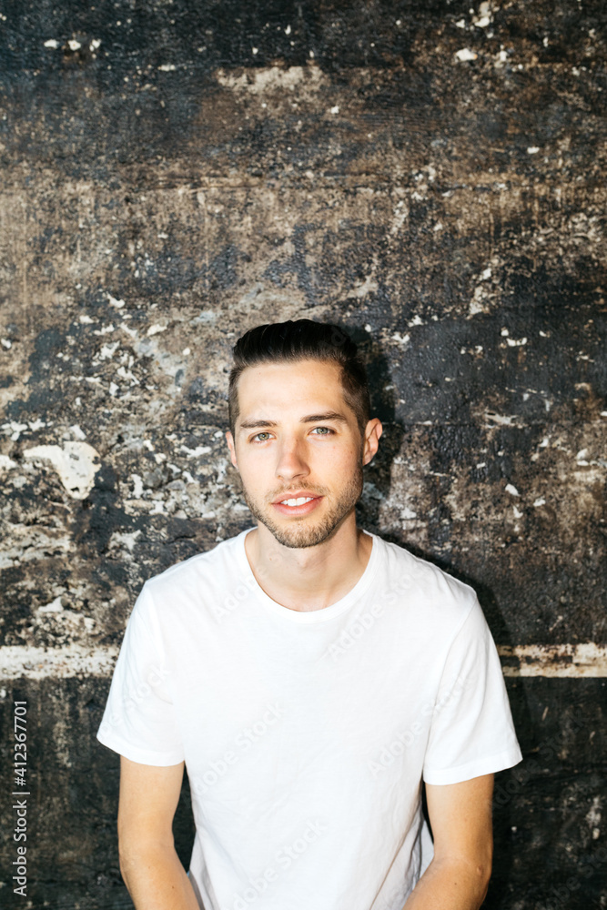 Portrait of young male against black concrete wall with bright flash on face. Portrait of young male against black concrete wall with bright flash on face.