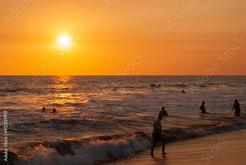 Silhouettes of people bathing on the public beach of Monterrico in Guatemala in the middle of the Covid-19 pandemic, sunset.