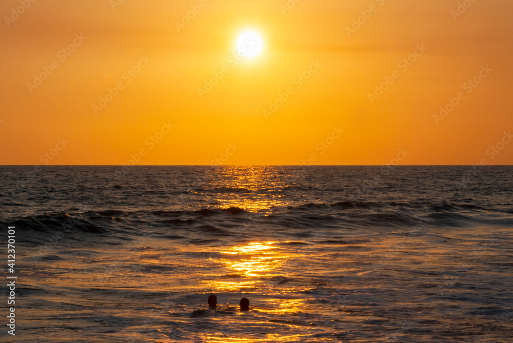 Silhouettes of people bathing on the public beach of Monterrico in Guatemala in the middle of the Covid-19 pandemic, sunset.