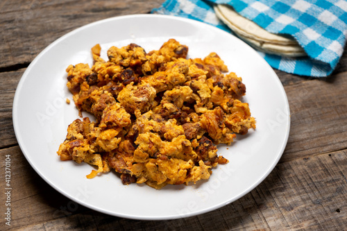 Scrambled eggs with chorizo for breakfast on wooden background. Mexican food