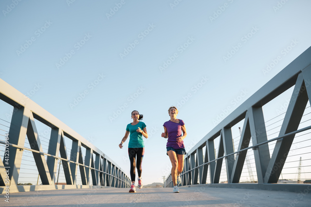 Healthy mature women on urban morning run together Healthy mature women on urban morning run together