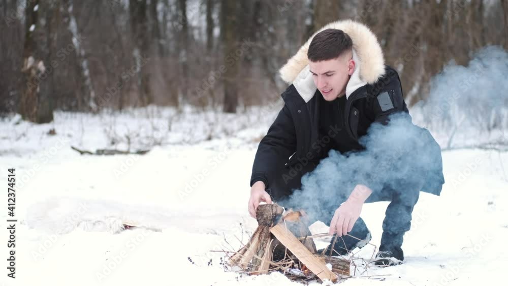 Young man making fire for bbq. Winter holidays. Countryside, snowy weather. Hiking concept. Young man making fire for bbq. Winter holidays. Countryside, snowy weather. Hiking concept.
