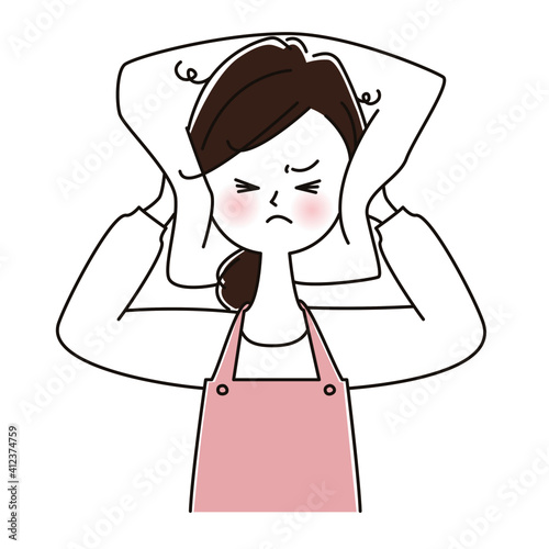 騒音でイライラして枕で耳をふさぐ　エプロン姿の女性