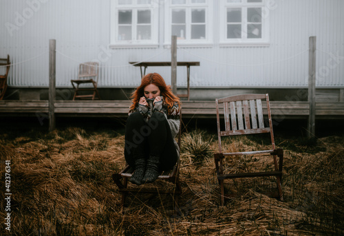ginger woman shrinking fro cold in the garden of a house