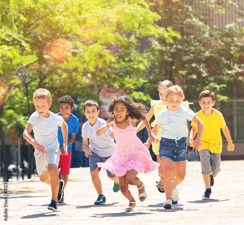 Team of positive kids running in race in the street and laughing outdoors