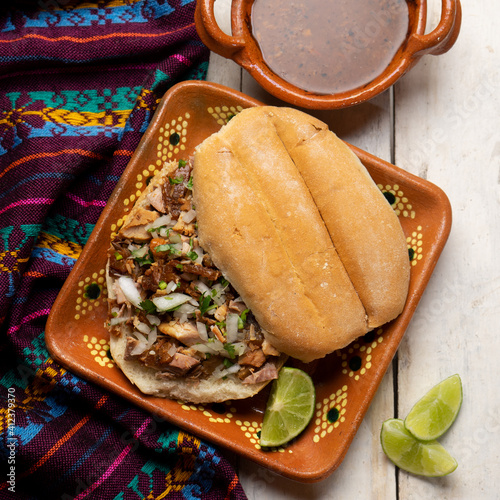 Confit pork sandwich called Torta de carnitas on white background. Mexican food photo