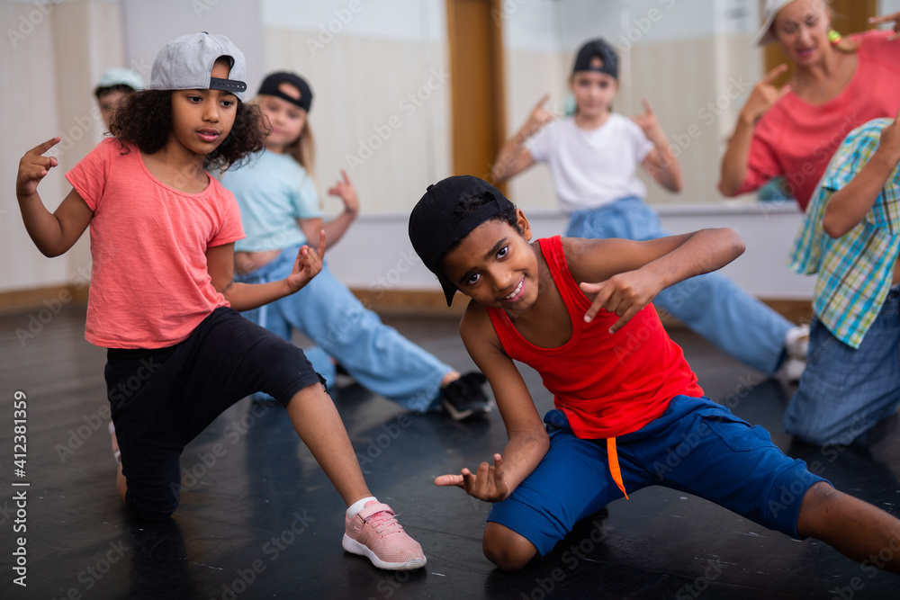 Obraz premium Positive girls and boys training hip hop in dance studio, dance classes for kids