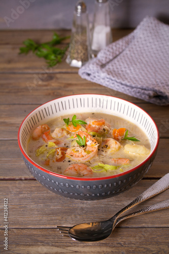 Shrimp prawn chowder with crab meat in a bowl on wooden table. vertical photo