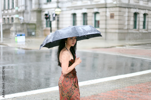 Woman in formal dress standing on a city corner in the rain photo