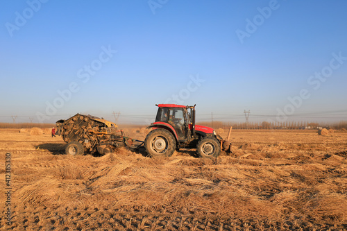 farmers use agricultural machinery to compress rice straw and bundle them on a farm, LUANNAN COUNTY, Hebei Province, China