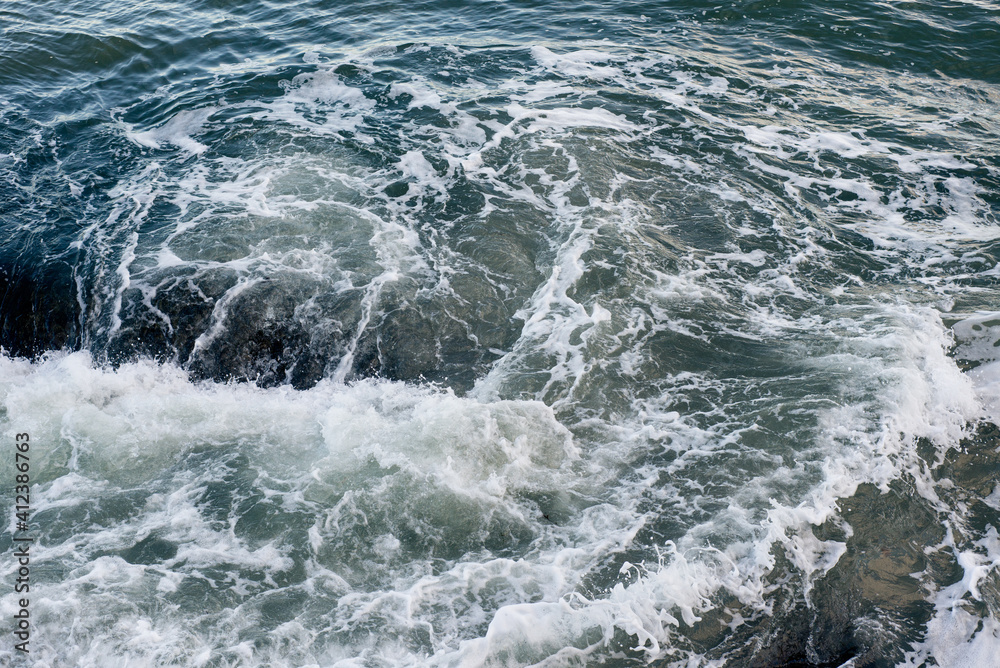 Waves breaking on underwater rocks, creating a small water vortex Waves breaking on underwater rocks, creating a small water vortex
