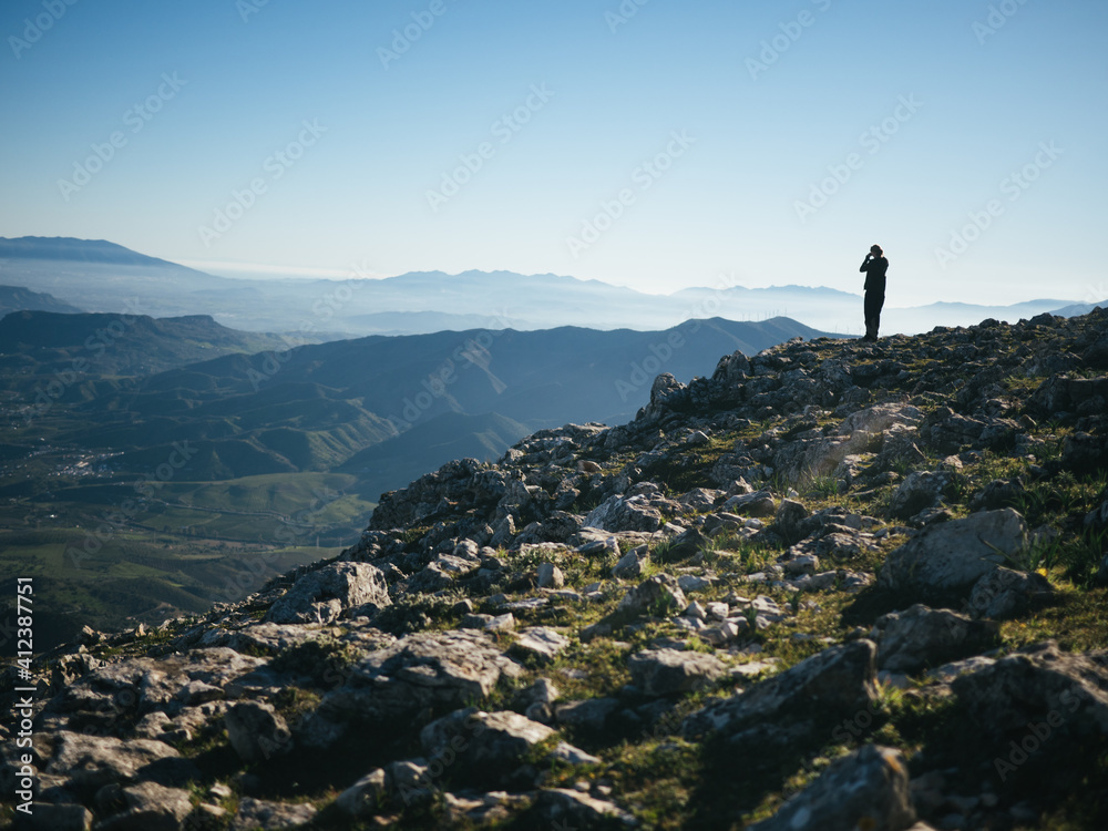 Miniature girl standing on top of mountain
