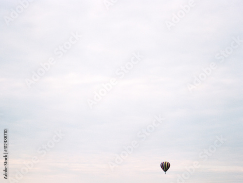 a tiny hot air balloon in a big pastel sky