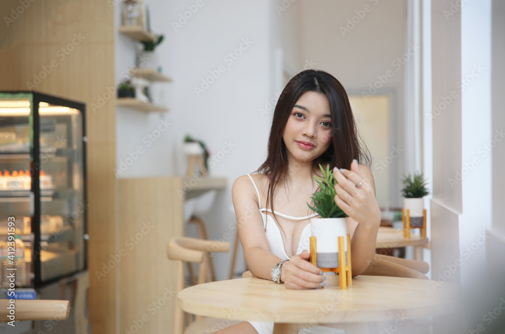 Portrait of Asian Young happy woman sitting alone in modern coffee shop interior.
