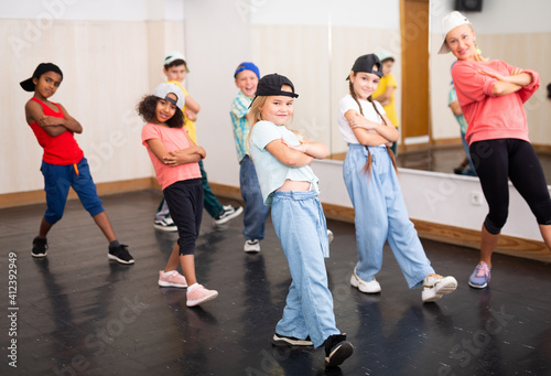 Portrait of preteen girl training movements of street hip-hop during group dance lesson ..