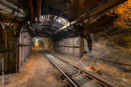 Tunnel of the mining of an underground mine. Lots of pipelines on the ceiling and rail track for trolleys