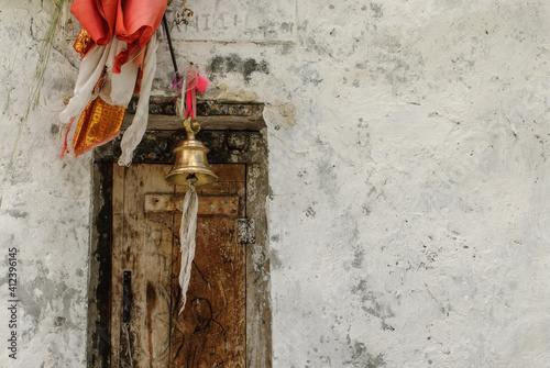 Old doorway with bell and silks, plaster wall has room for text.