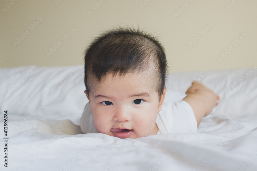 Little baby lying on stomach, looking at camera and sticking tongue out Little baby lying on stomach, looking at camera and sticking tongue out