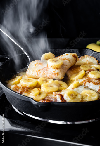 Close up of Banana Foster cooking and steaming in a cast iron skillet.