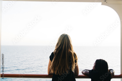 Mother and daughter looking at the ocean from the deck of a cruise ship photo