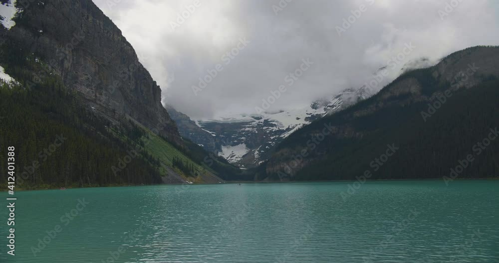 Pure mountain water flowing in a river in great valley with forest growing on slopes of huge hills and snow-covered mountains Pure mountain water flowing in a river in great valley with forest growing on slopes of huge hills and snow-covered mountains