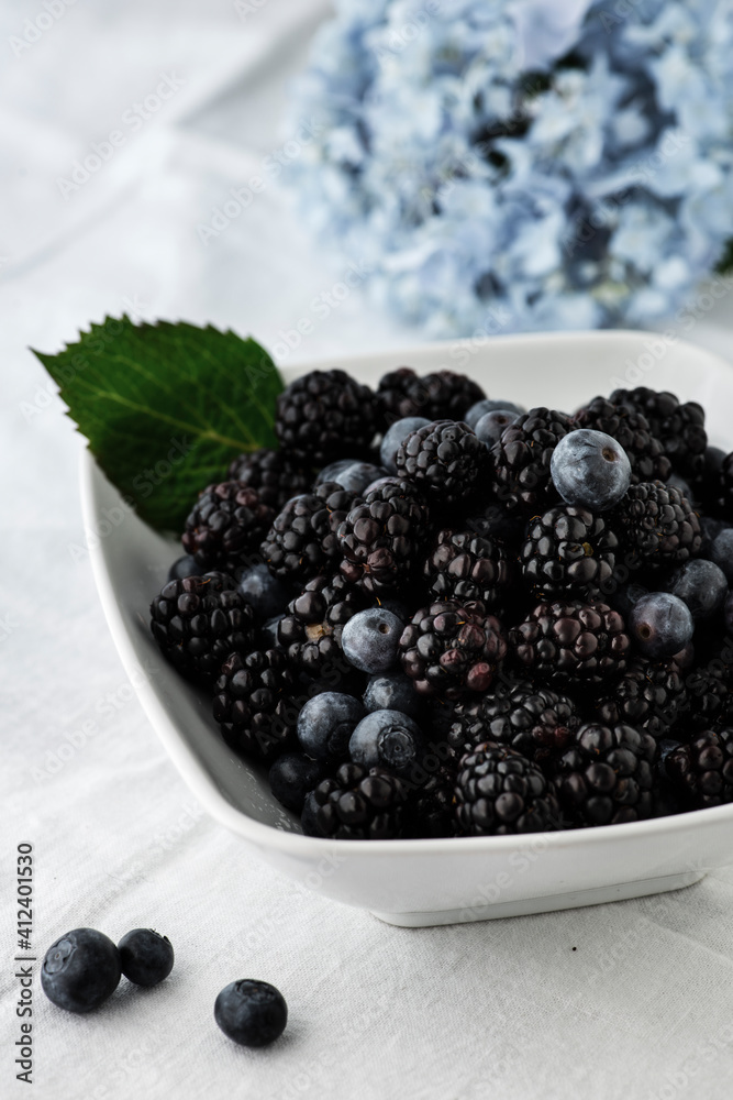 Bowl of Blackberries and blueberries with a blue hydrangea flower Bowl of Blackberries and blueberries with a blue hydrangea flower