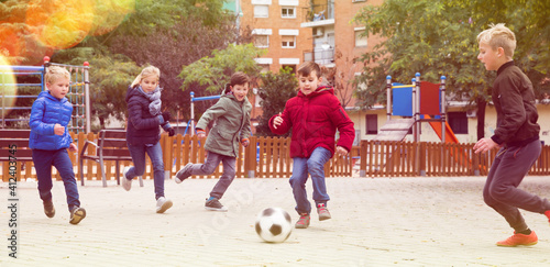 Children active games. Interested happy kids playing football outdoors in autumn day