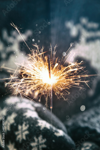 Woman wearing mittens holding a sparkler photo