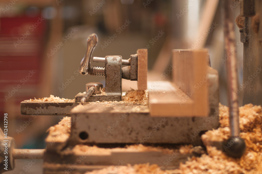 A hand vice on a workbench covered in sawdust A hand vice on a workbench covered in sawdust