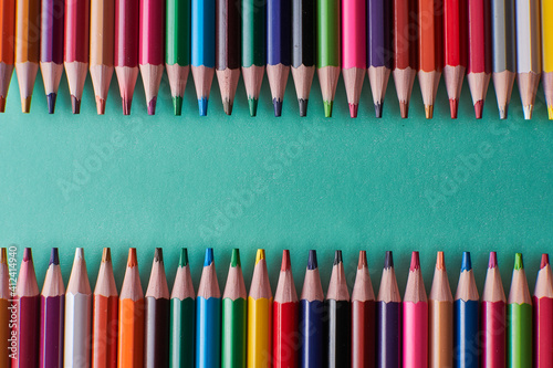 Pencils of different sizes on green background