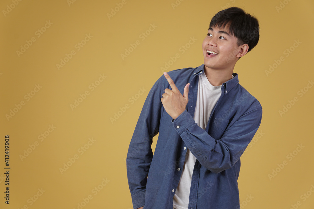 portrait of happy young asian man dressed casually pointing finger up at copyspace. yellow background portrait of happy young asian man dressed casually pointing finger up at copyspace. yellow background