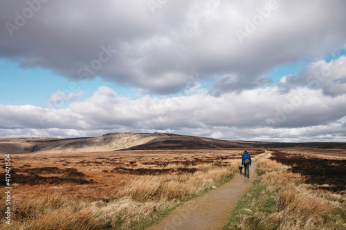 Male and his dog, walking a footpath through moorland on Bleaklow, Derbyshire, UK.