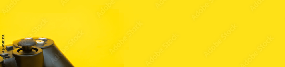 Crop black joystick gaming controller on trendy yellow background, banner with space for text: video game console concept for Interactive Entertainment gamer Crop black joystick gaming controller on trendy yellow background, banner with space for text: video game console concept for Interactive Entertainment gamer