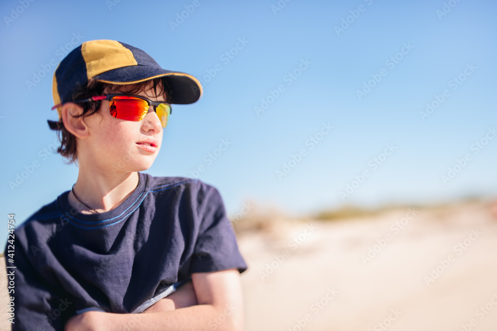 Boy with cap and sunglasses at the beach on a sunny afternoon Boy with cap and sunglasses at the beach on a sunny afternoon