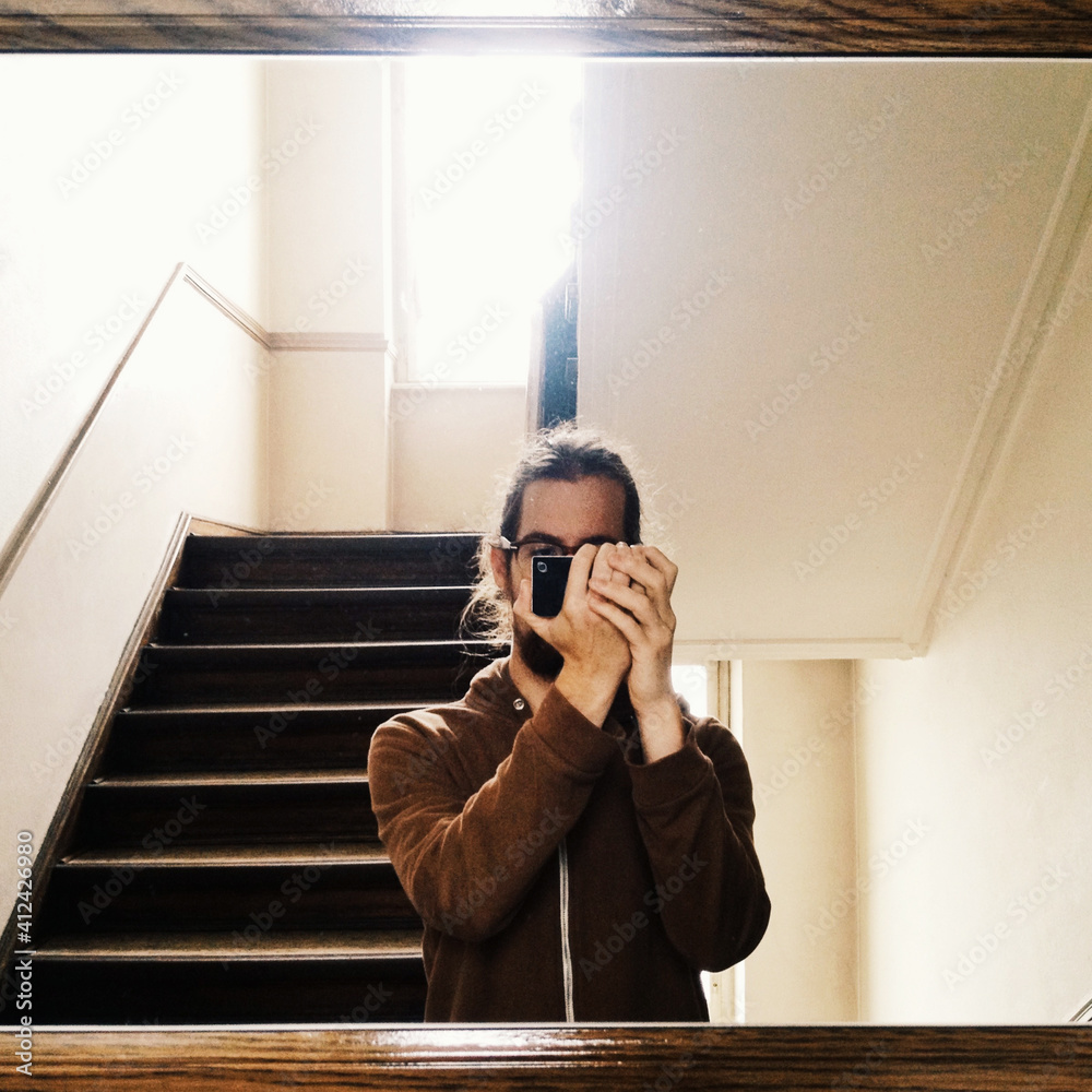 Young man taking self portrait with mobile phone, wearing all brown. Young man taking self portrait with mobile phone, wearing all brown.