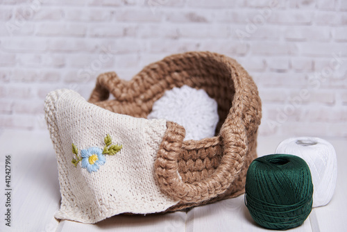 handmade knitted basket on a wooden table. Next to the thread in the skeins for yarn. Cozy arrangement of the house made of ecological materials