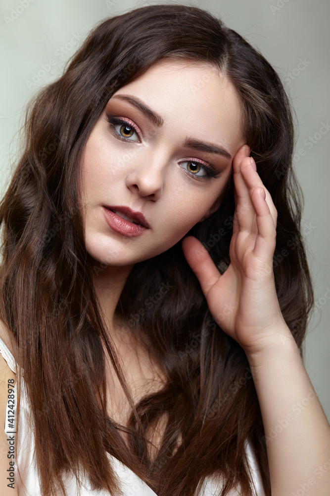 Beauty portrait of young woman. Brunette girl with evening female makeup and black dess Beauty portrait of young woman. Brunette girl with evening female makeup and black dess