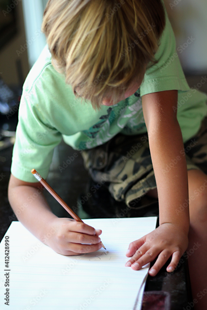 Young boy doing his homework, writing with pencil Young boy doing his homework, writing with pencil