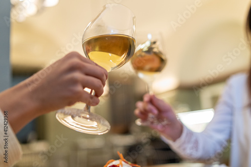 Close up shot of young people couple holding glasses with white wine and clinking them with a celebratory toast