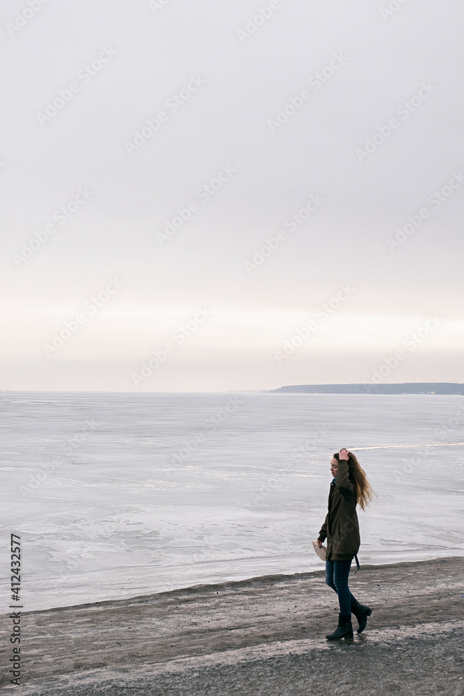 Side view of teenage girl walking along coastline with map Side view of teenage girl walking along coastline with map
