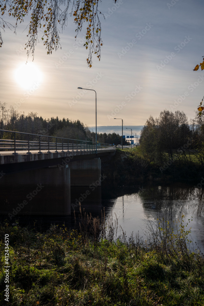 Besides a main road in Finland with low sun with a bridge and river