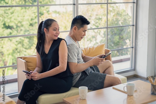 Asian man and woman family in casual outfit sitting in living room using smart tablet or mobile phone together in happy and smile emotion