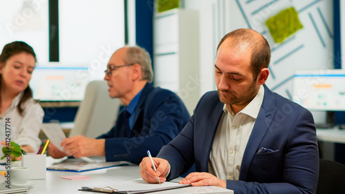 Bild auf Leinwand Businessman reading paper document, discussing contract with confident partner, signing investment papers