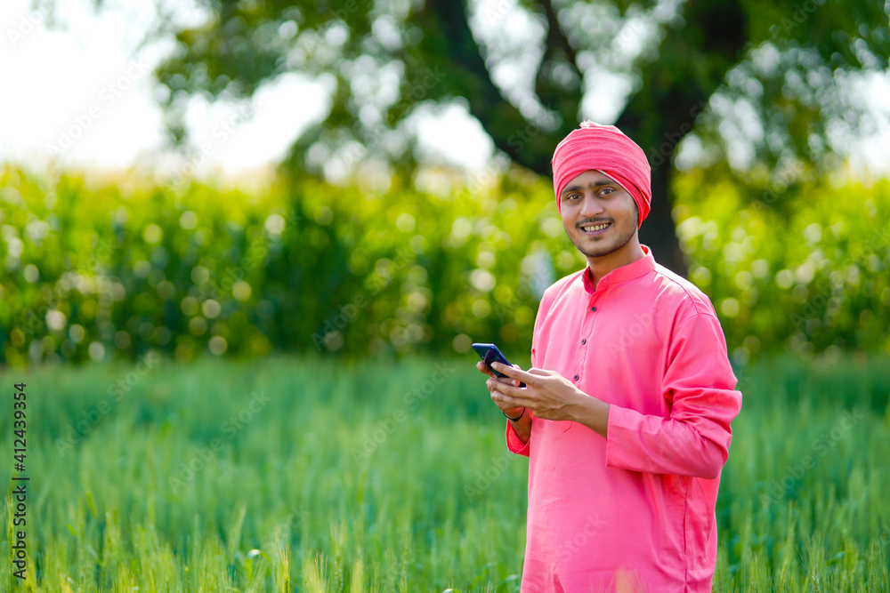 Young indian farmer using smartphone at wheat field Young indian farmer using smartphone at wheat field