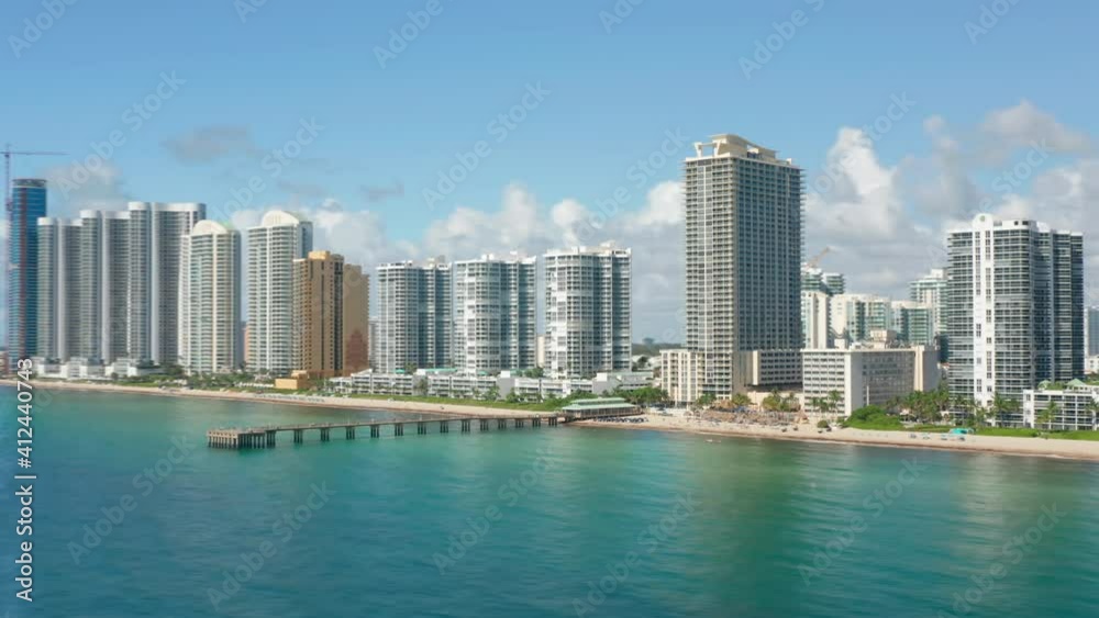 Hyper lapse Miami beach city skyline. Scenic modern cityscape, aerial drone water. White design skyscraper buildings on beach with ocean view apartments. Blue sky and white clouds on motion background Hyper lapse Miami beach city skyline. Scenic modern cityscape, aerial drone water. White design skyscraper buildings on beach with ocean view apartments. Blue sky and white clouds on motion background