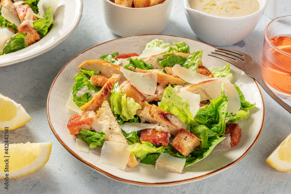 Chicken Caesar salad close-up. Grilled chicken, romaine leaves, croutons and Parmesan