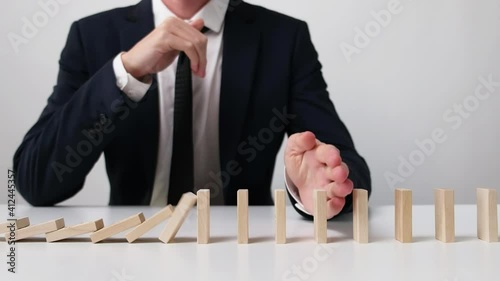 Businessman Stopped the Falling Domino Effect. Slow Motion. photo